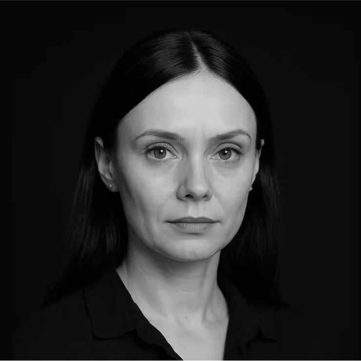 Black and white portrait of a woman with long dark hair wearing a dark shirt against a black background.