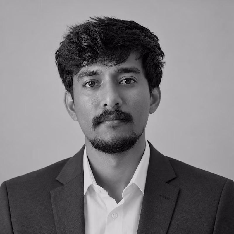 Black and white portrait of Prudhvi Koduru on a light gray studio background.