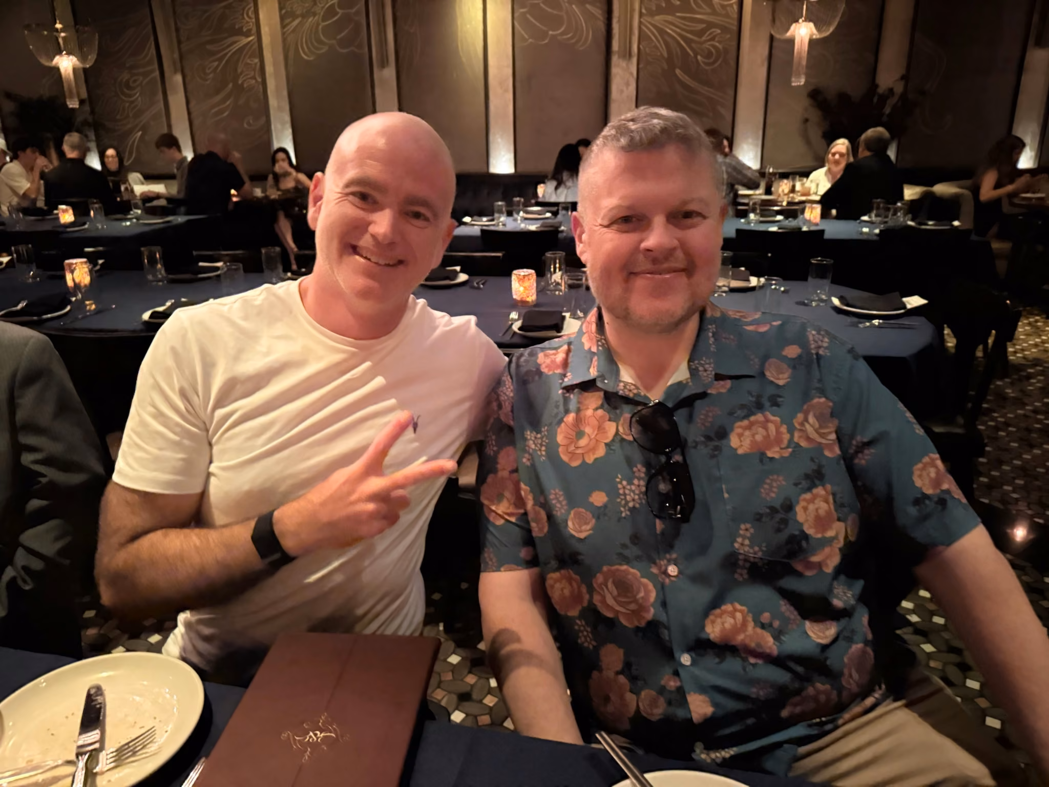 Two colleagues at a Las Vegas dinner, one flashing a peace sign