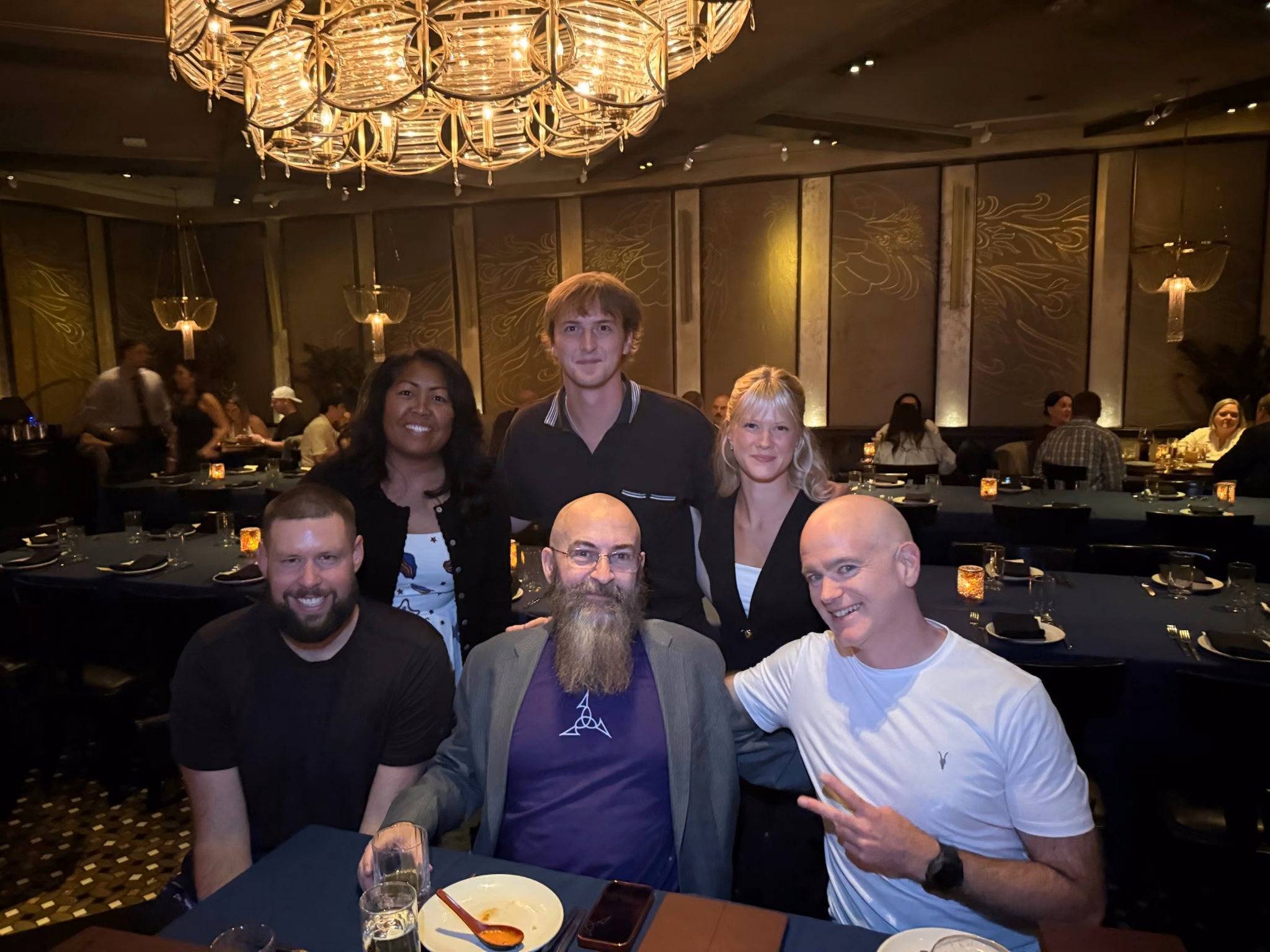 The YSecurity team and friends at dinner under a chandelier in Las Vegas