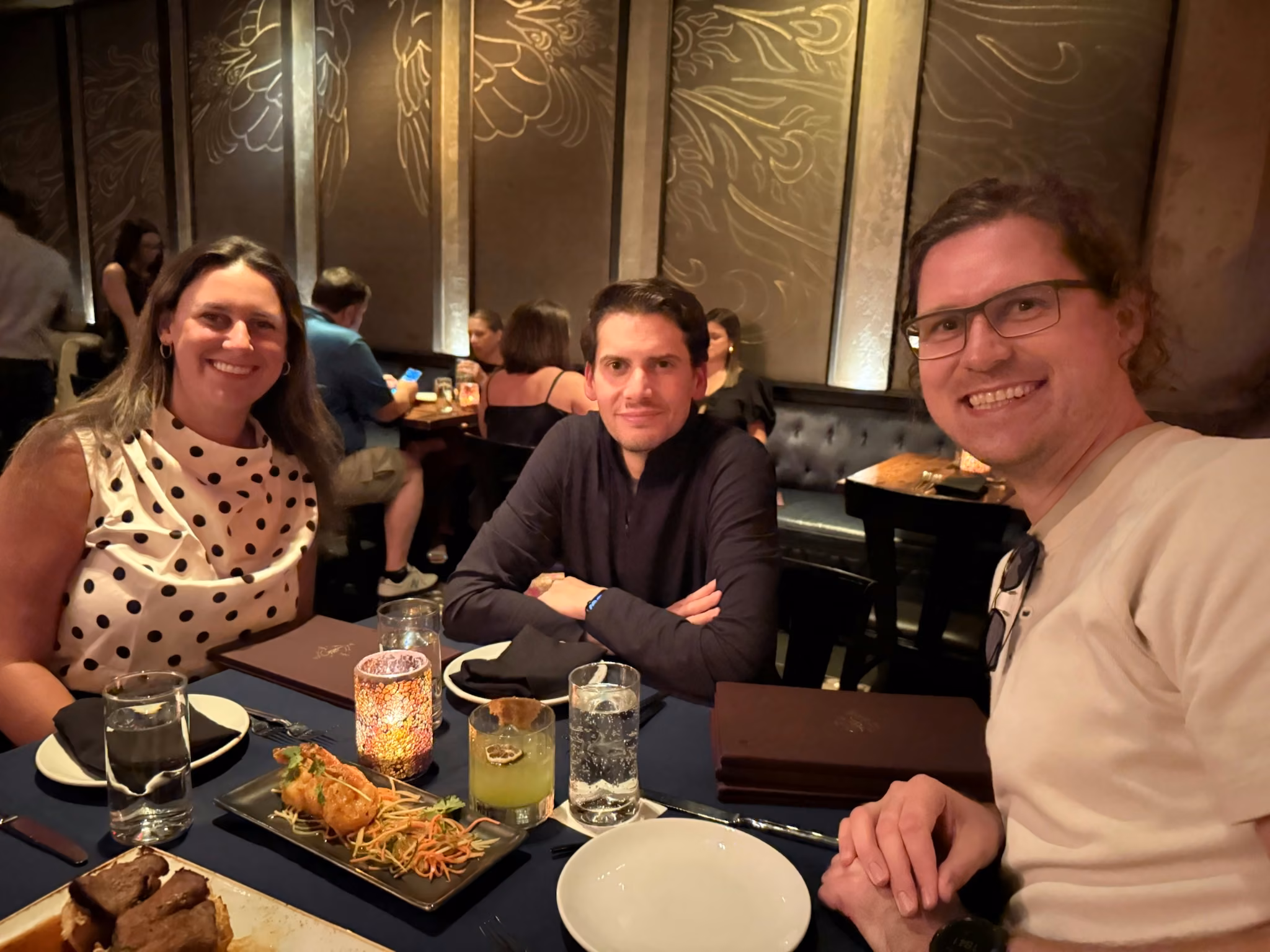Three of the team smiling over dinner and cocktails