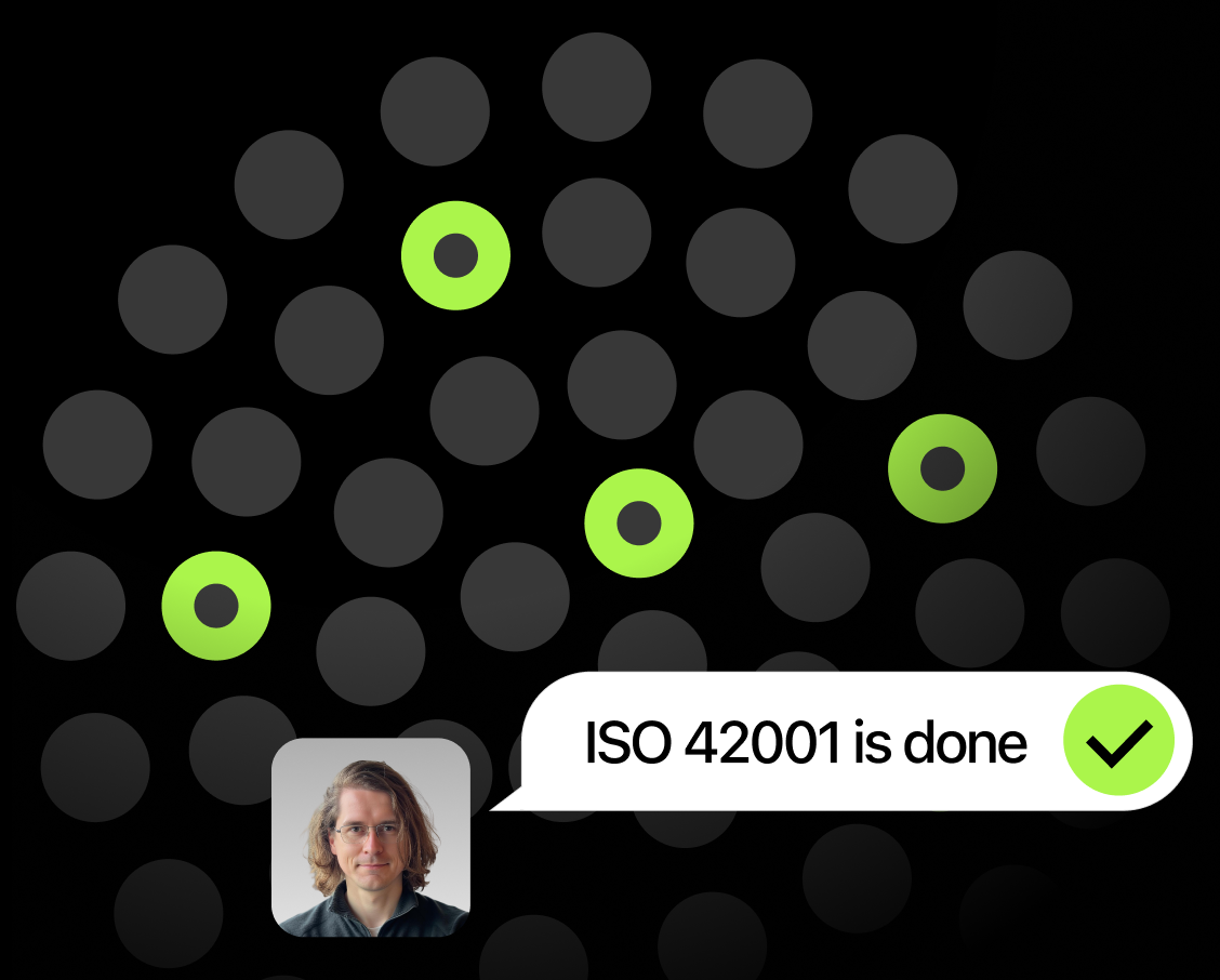 Chat bubble stating 'ISO 42001 is done' with a green checkmark next to a profile photo of a man with glasses and medium-length hair, on a background of dark and green circles.
