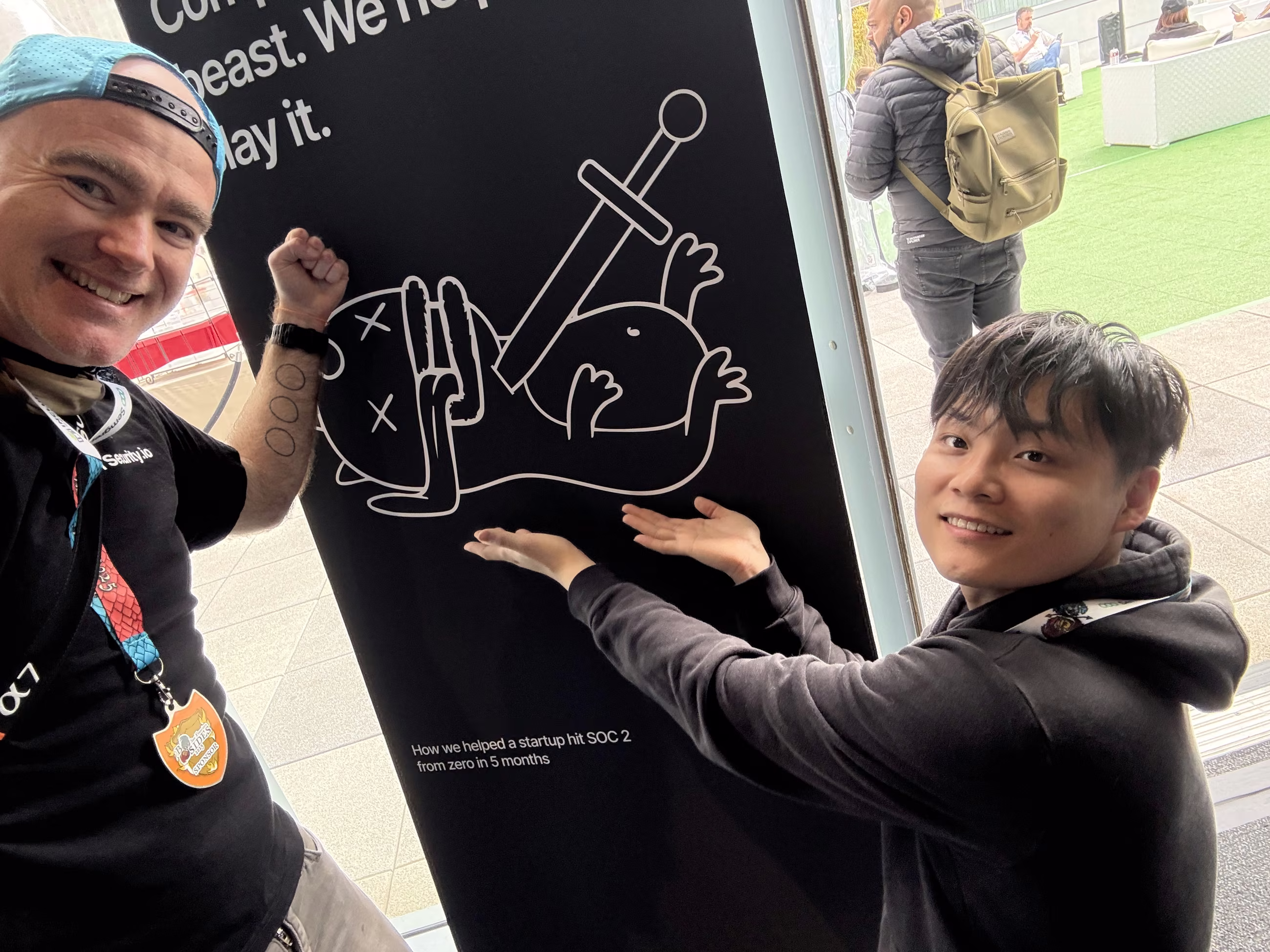 Two team members pointing at the slain compliance-beast mural