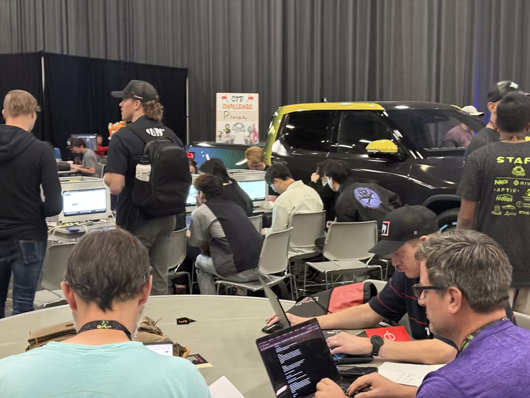 The Car Hacking Village at DEF CON 33 in Las Vegas, with laptops open on tables around a car as attendees work on its systems