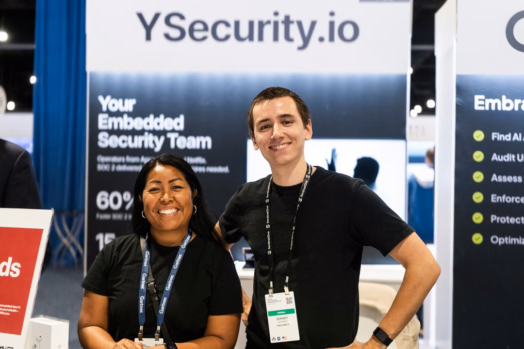Two YSecurity team members at the YSecurity.io booth wall on the expo floor of the Gartner Security and Risk Management Summit