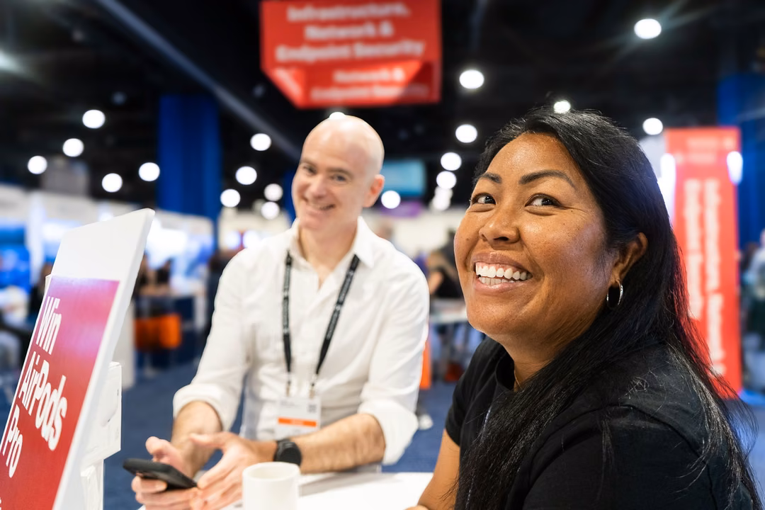 Two people in conversation at a table on the expo floor of the Gartner Security and Risk Management Summit in National Harbor