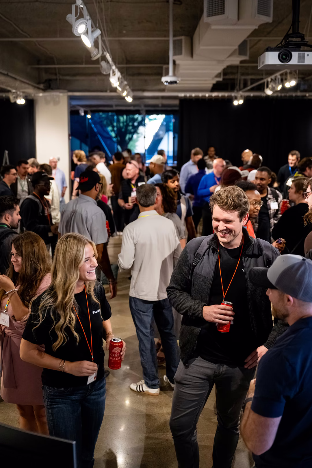 Kailyn Lund and a YSecurity teammate laughing with attendees in a packed room at Innovation Day during Twin Cities Startup Week
