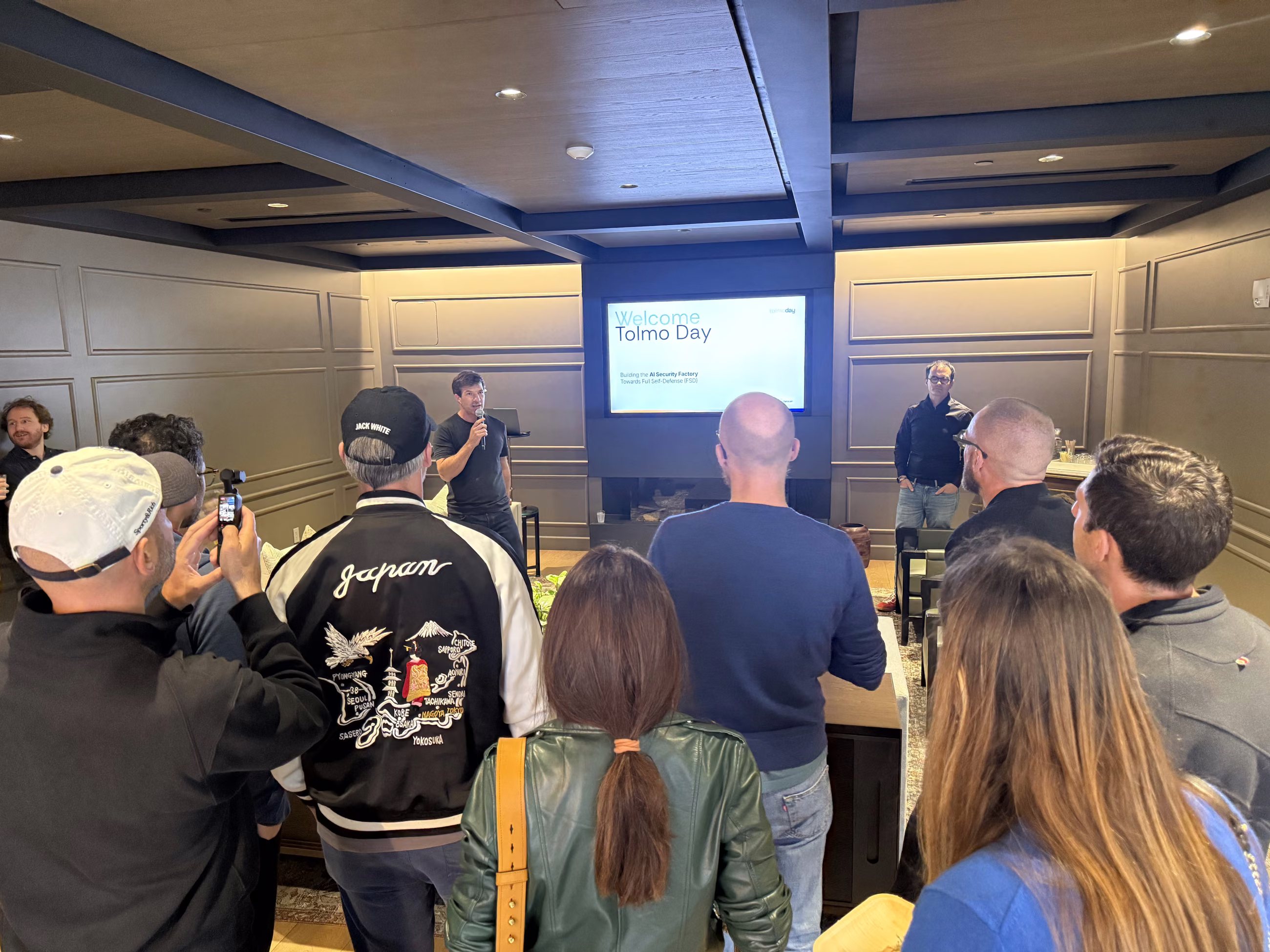 Pierre Betouin speaking to a standing crowd in front of a “Welcome to Tolmo Day” screen at Accel in San Francisco